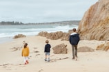 A family enjoying a seaside walk along rugged cliffs with waves crashing below.
