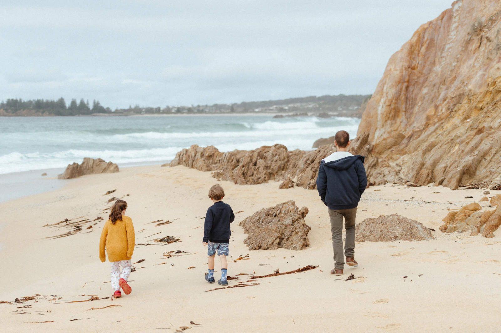 Un parent et deux enfants marchent sur une plage lors d'une escapade en famille
