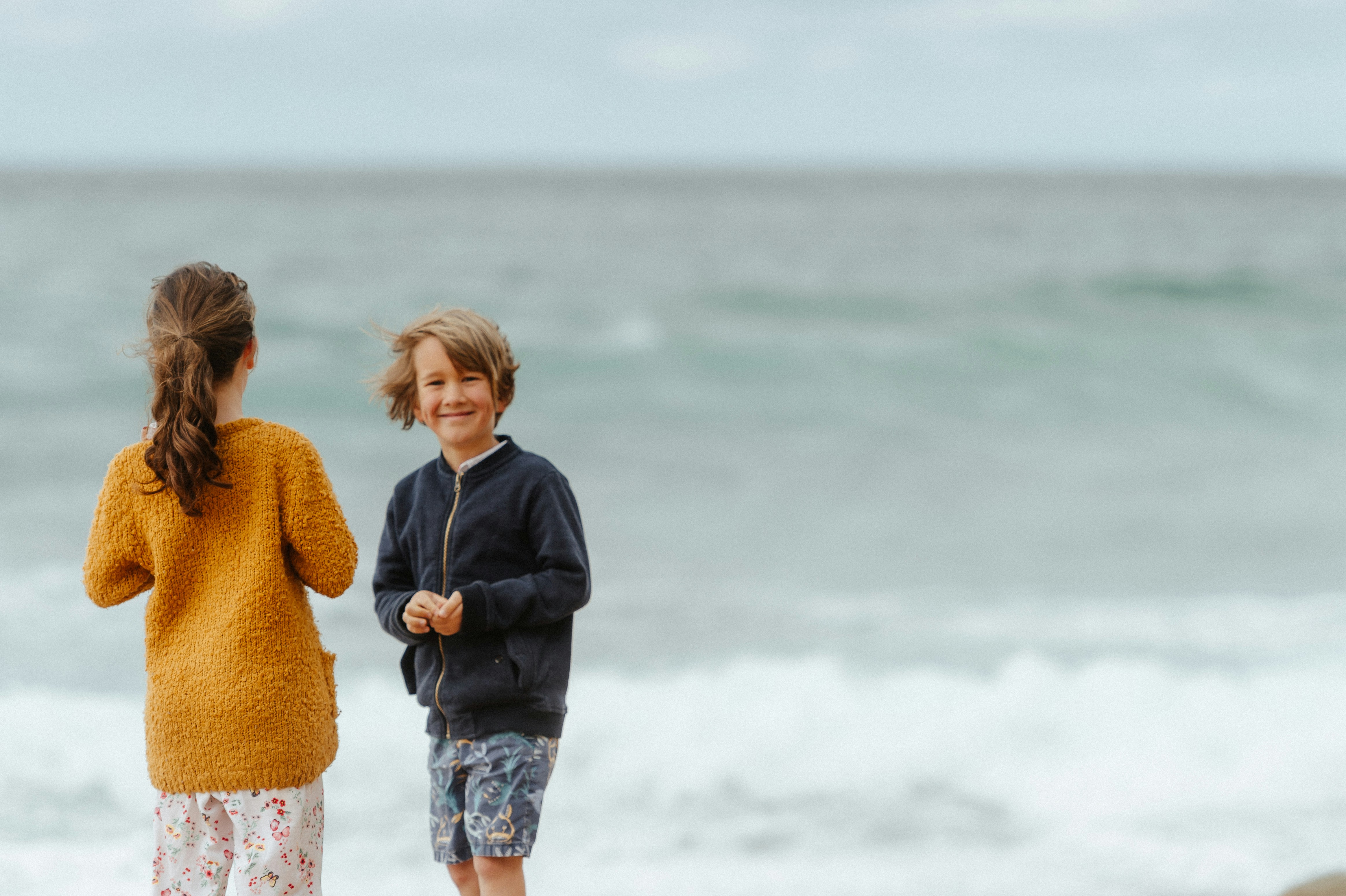 a couple of kids standing on top of a beach
