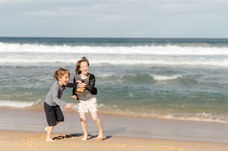 a couple of kids playing on a beach