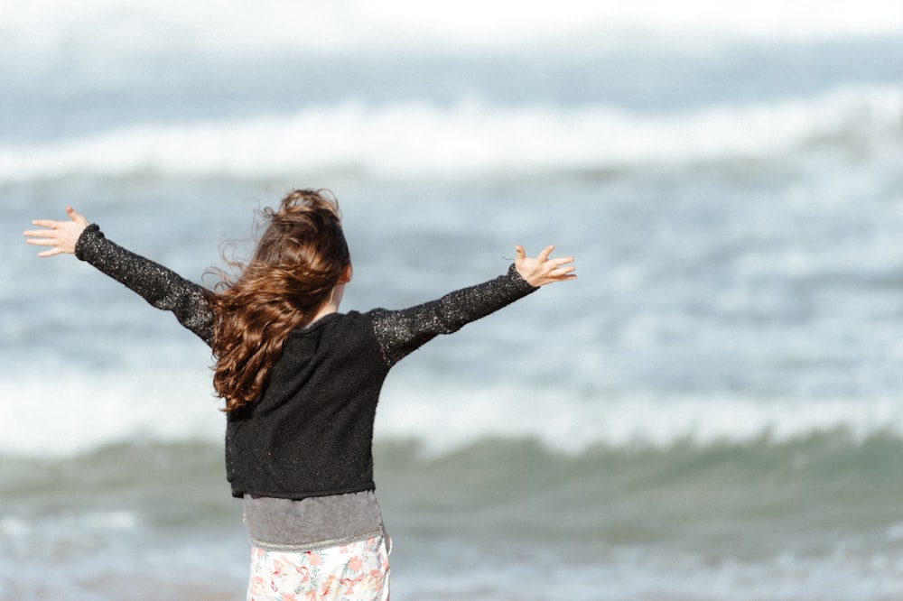 a woman standing on a beach with her arms outstretched