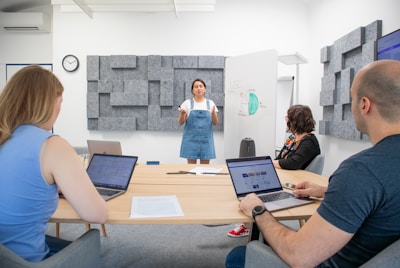 a group of people sitting around a table with laptops