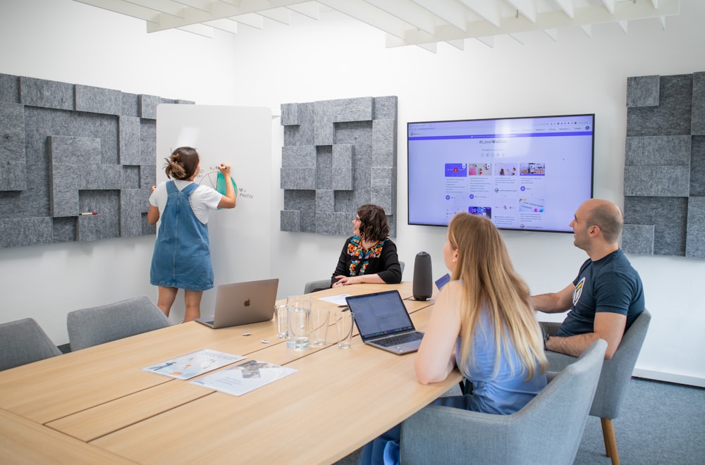 um grupo de pessoas sentadas ao redor de uma mesa com laptops