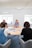 Photo of a small group engaged in a meeting around a wooden table with natural light.