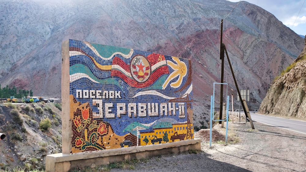 a sign on the side of a road with mountains in the background
