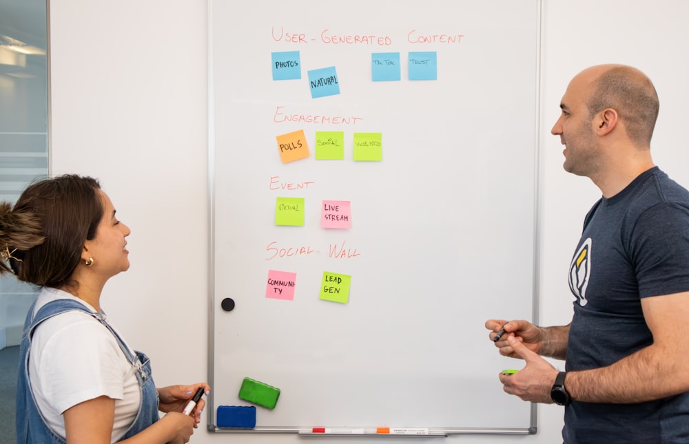 a man and a woman standing in front of a white board