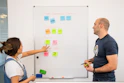 a man and a woman standing in front of a whiteboard