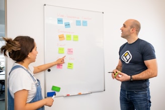 a man and a woman standing in front of a white board