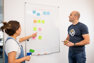 a man and a woman standing in front of a white board