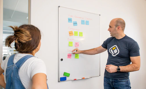 a man and a woman standing in front of a white board