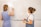 Two people are writing on a whiteboard, discussing the setup process for a social wall. The board is divided into sections labeled: setup, add sources, customize, and share. One person is wearing a blue dress and the other is wearing denim overalls.