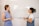Two people are standing in front of a whiteboard discussing a topic titled 'How to Set Up a Social Wall'. The whiteboard outlines steps: Sign up, Add Sources, Customize, and Share. One person is holding a marker, and both are engaged in conversation, likely explaining the steps.