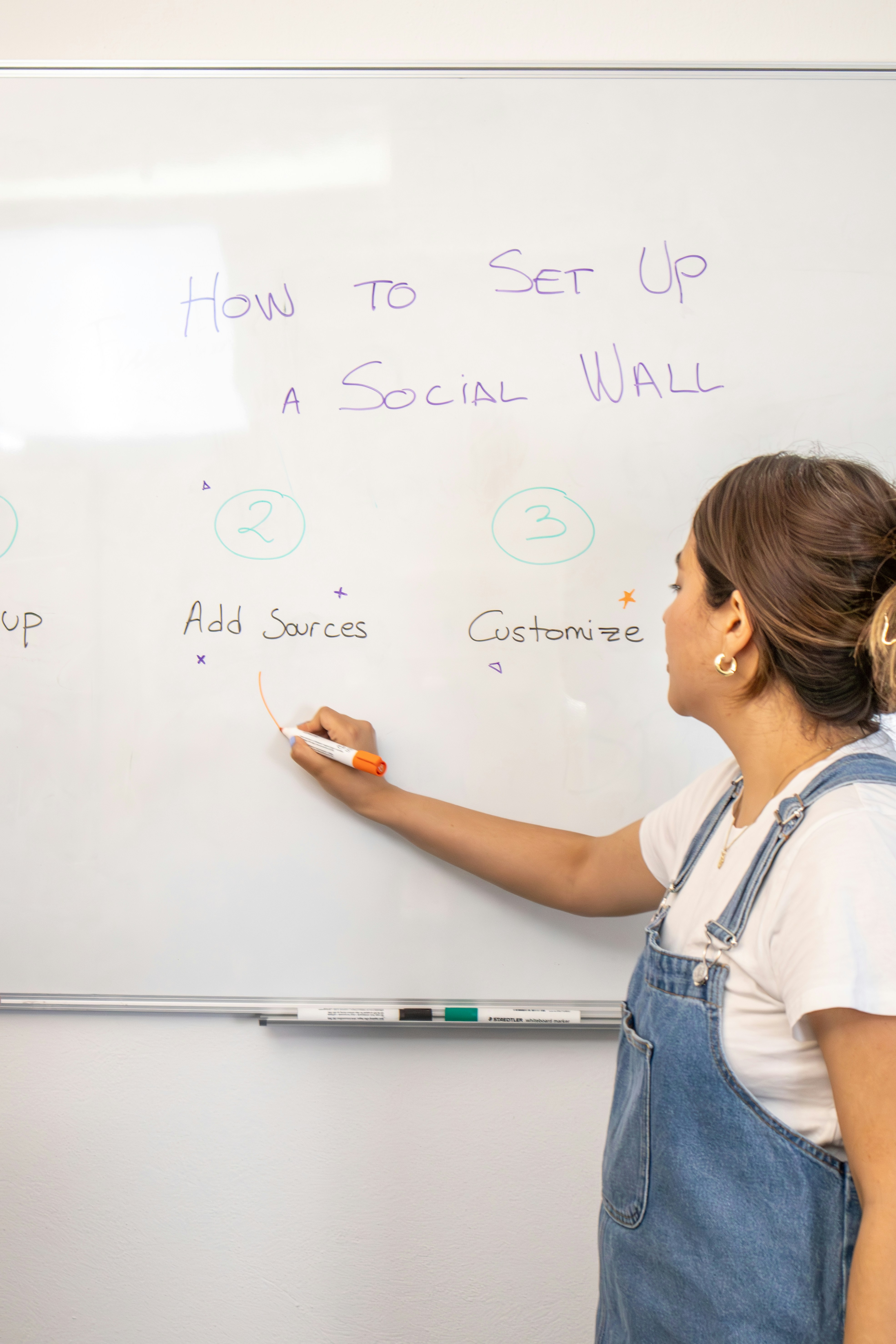 a woman writing on a white board with marker