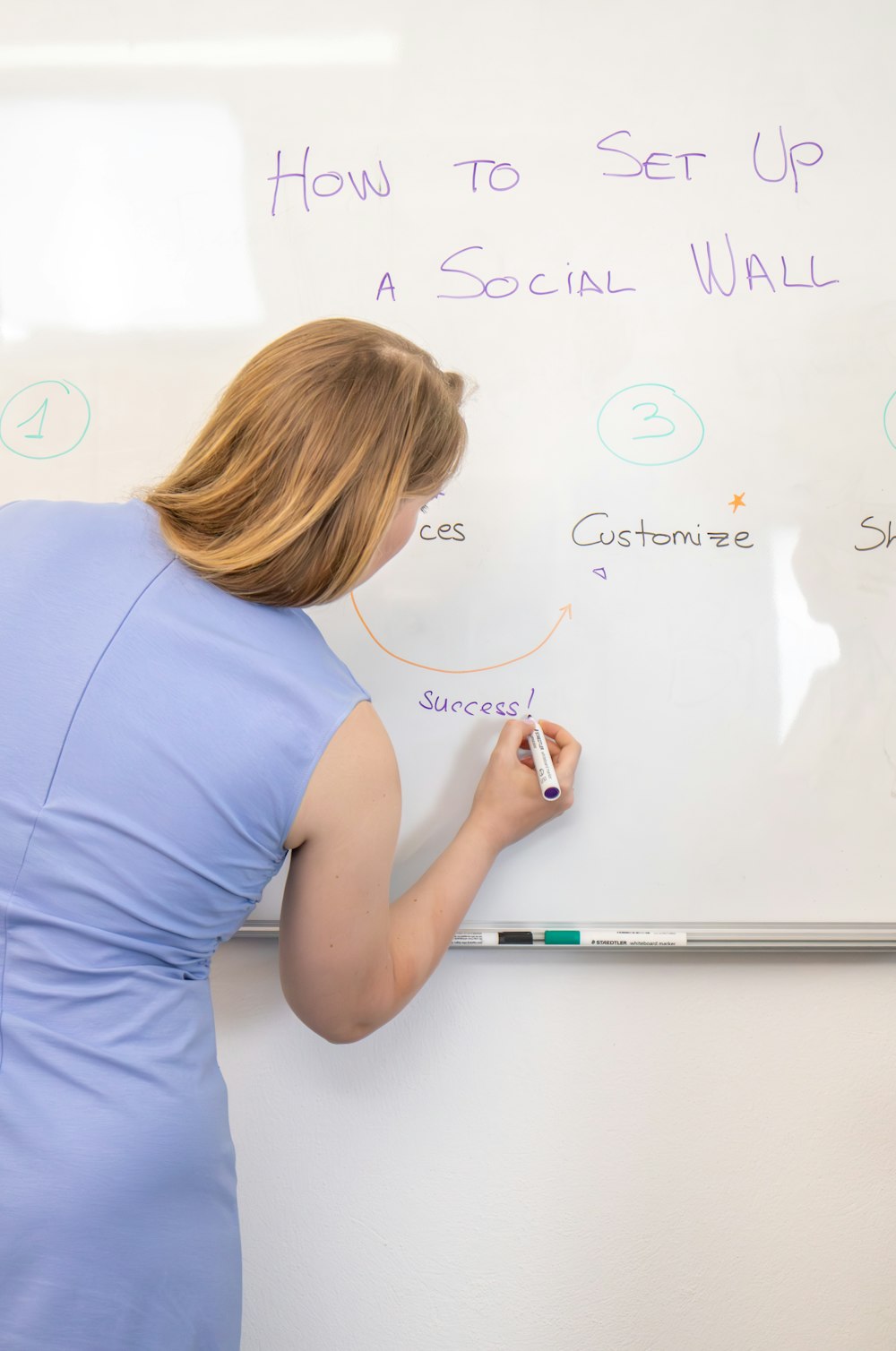 a woman writing on a white board with marker