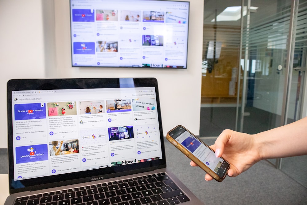 a person holding a cell phone in front of a laptop