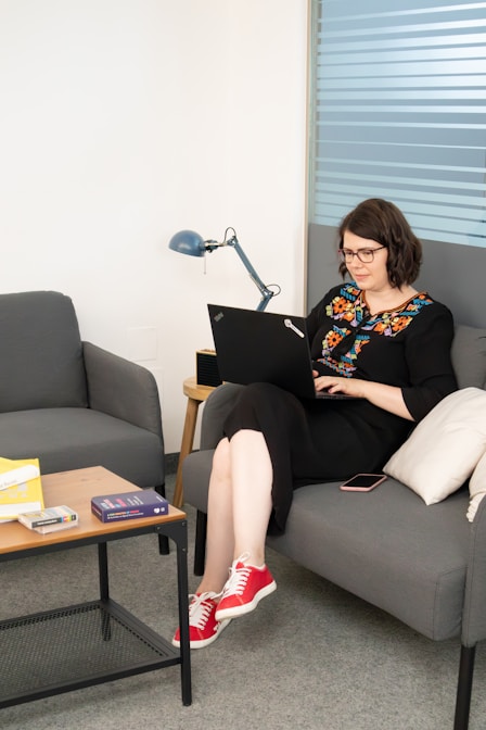 a woman sitting on a couch using a laptop computer