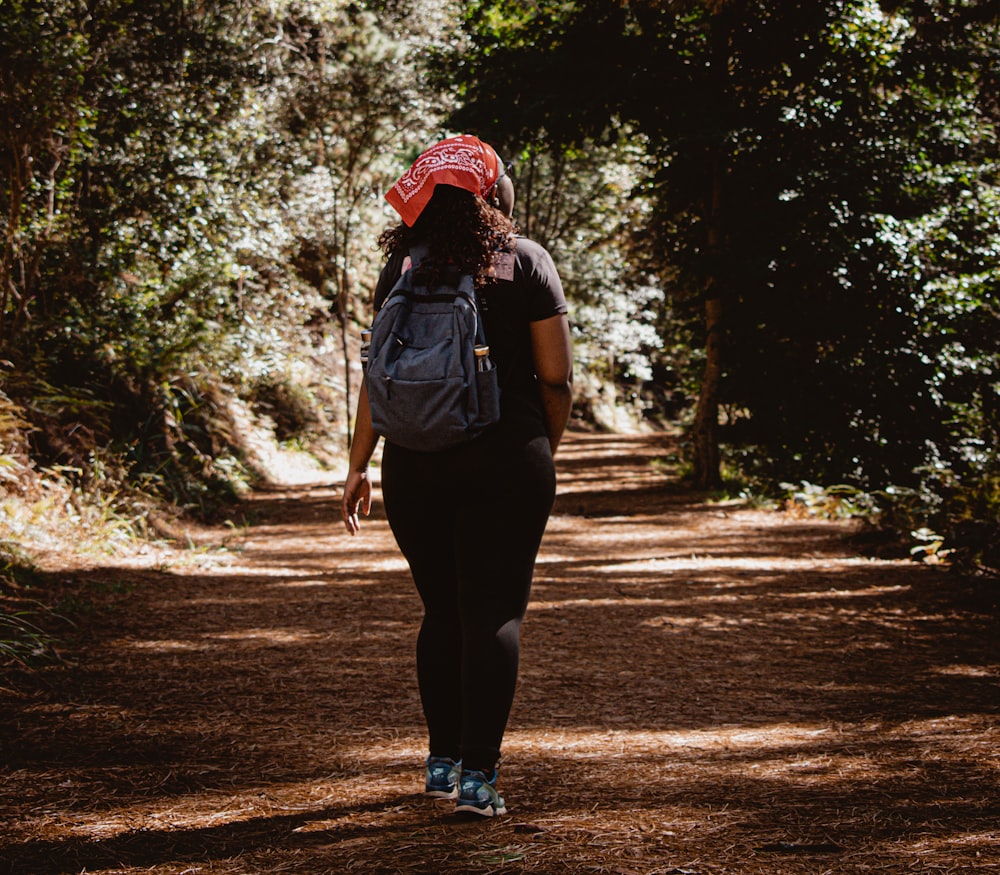 a woman with a backpack walking down a dirt road