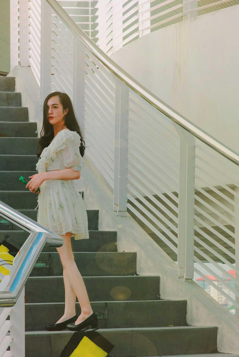 a woman in a white dress walking down a flight of stairs