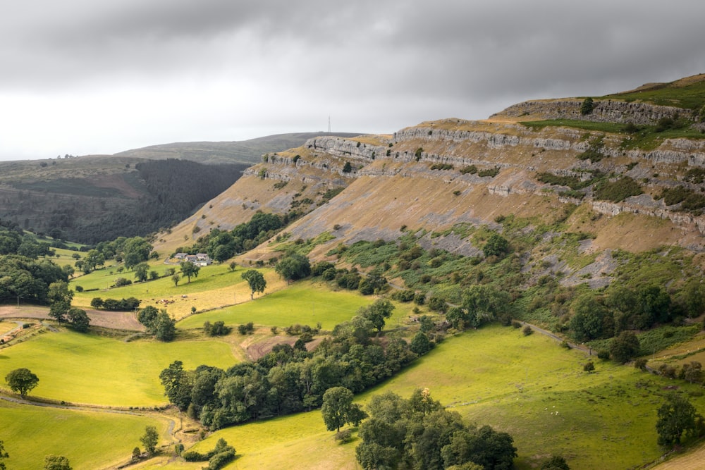 a lush green valley surrounded by mountains under a cloudy sky