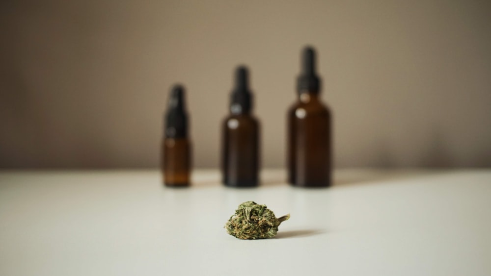 three bottles and a marijuana bud on a table