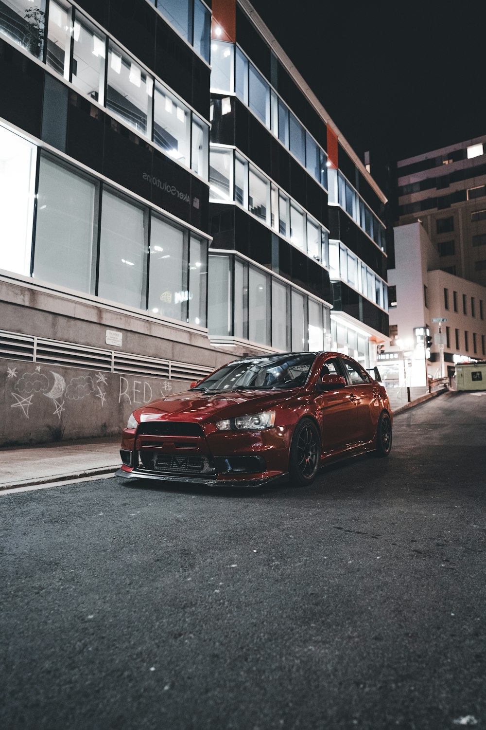 a red car parked in front of a tall building