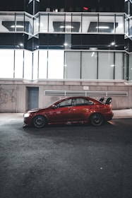A sleek red and black rental car parked in front of a modern city backdrop.