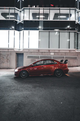 A sleek maroon sedan parked on a city street under soft natural light, showcasing a realistic and polished look.