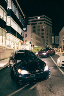 Nighttime cityscape with a row of parked luxury cars under soft street lighting, highlighting sleek silhouettes