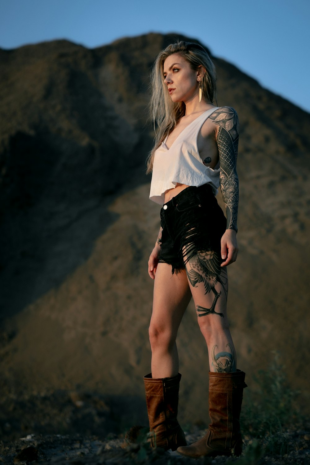 a woman with tattoos standing in front of a mountain