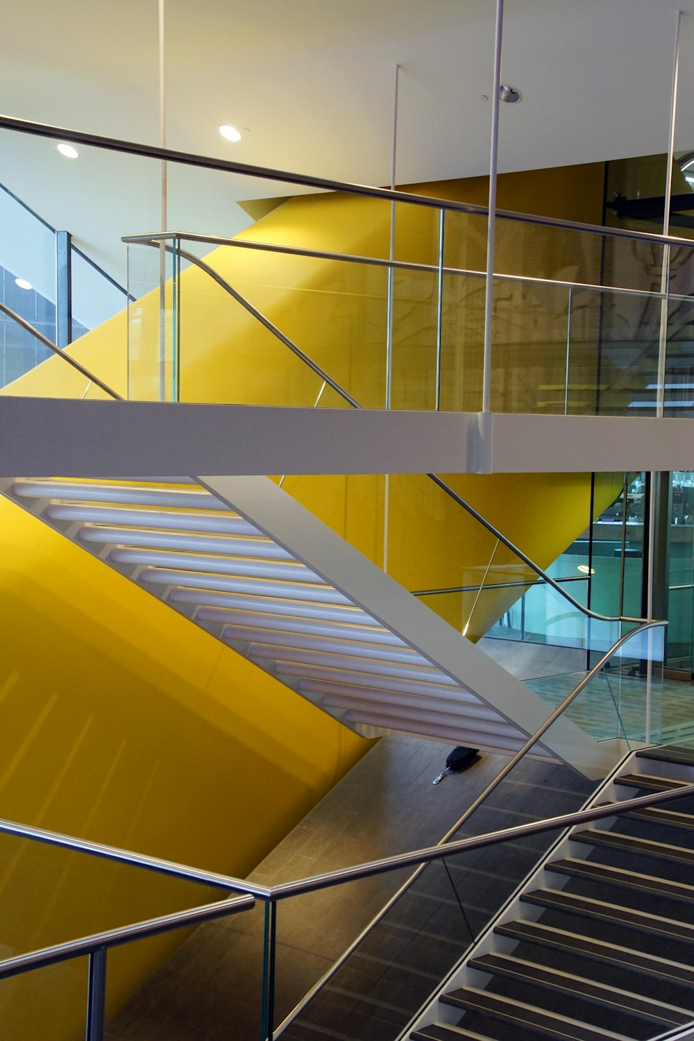 a yellow staircase in a building with glass balconies