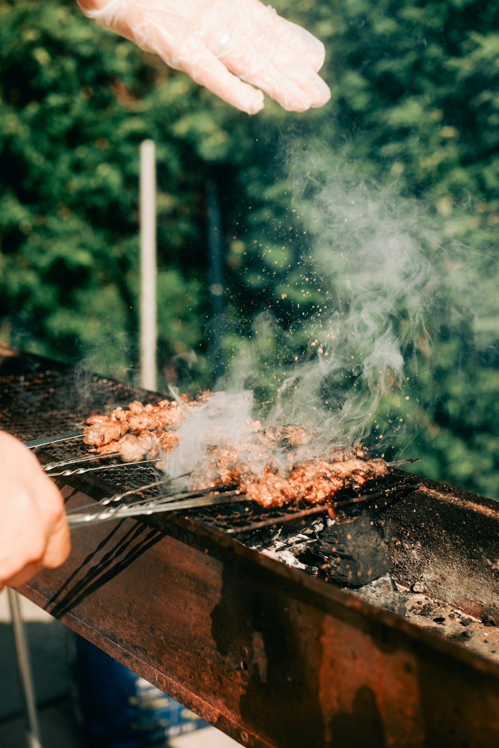 a person in white gloves cooking food on a grill