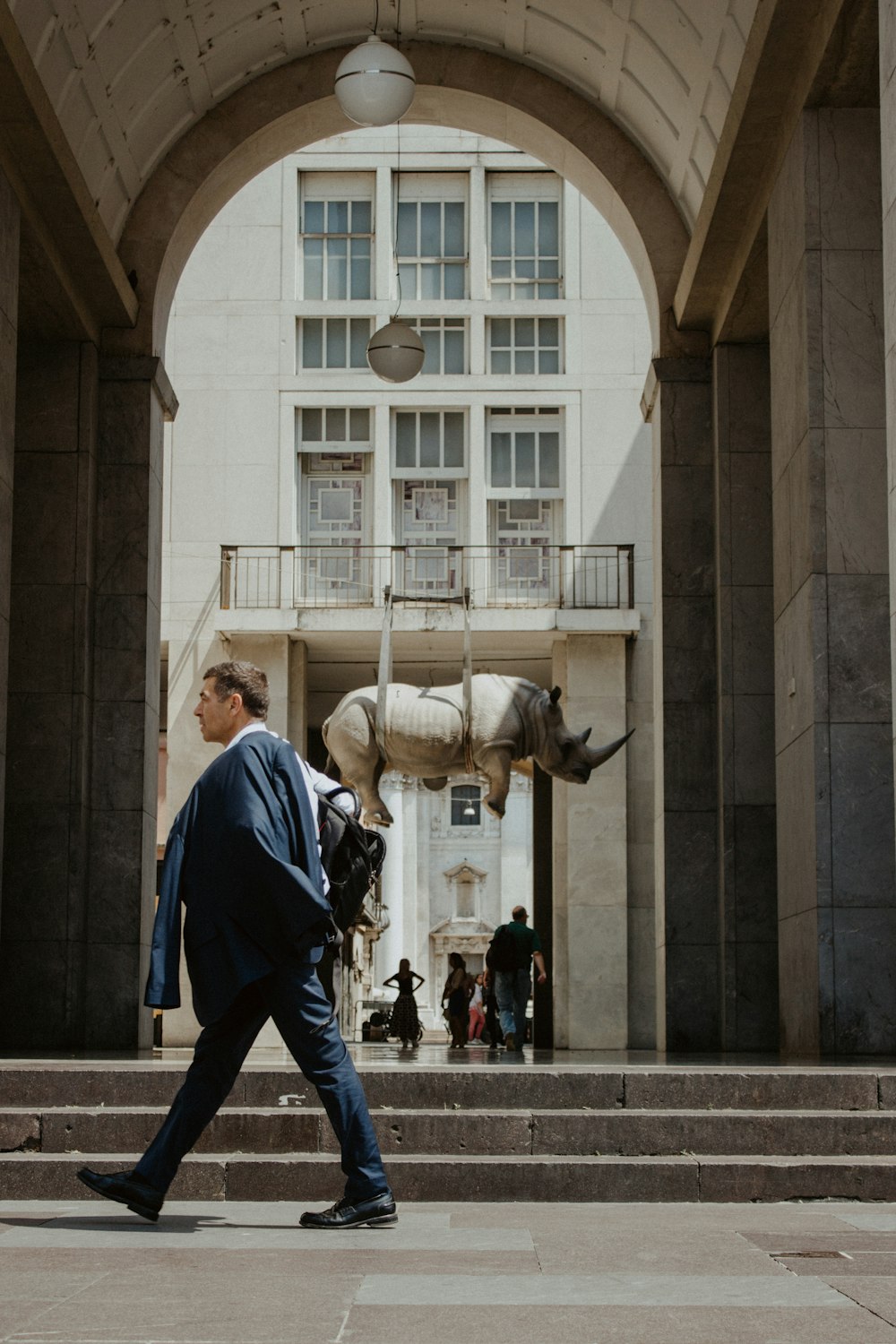 a man in a suit walking past a building