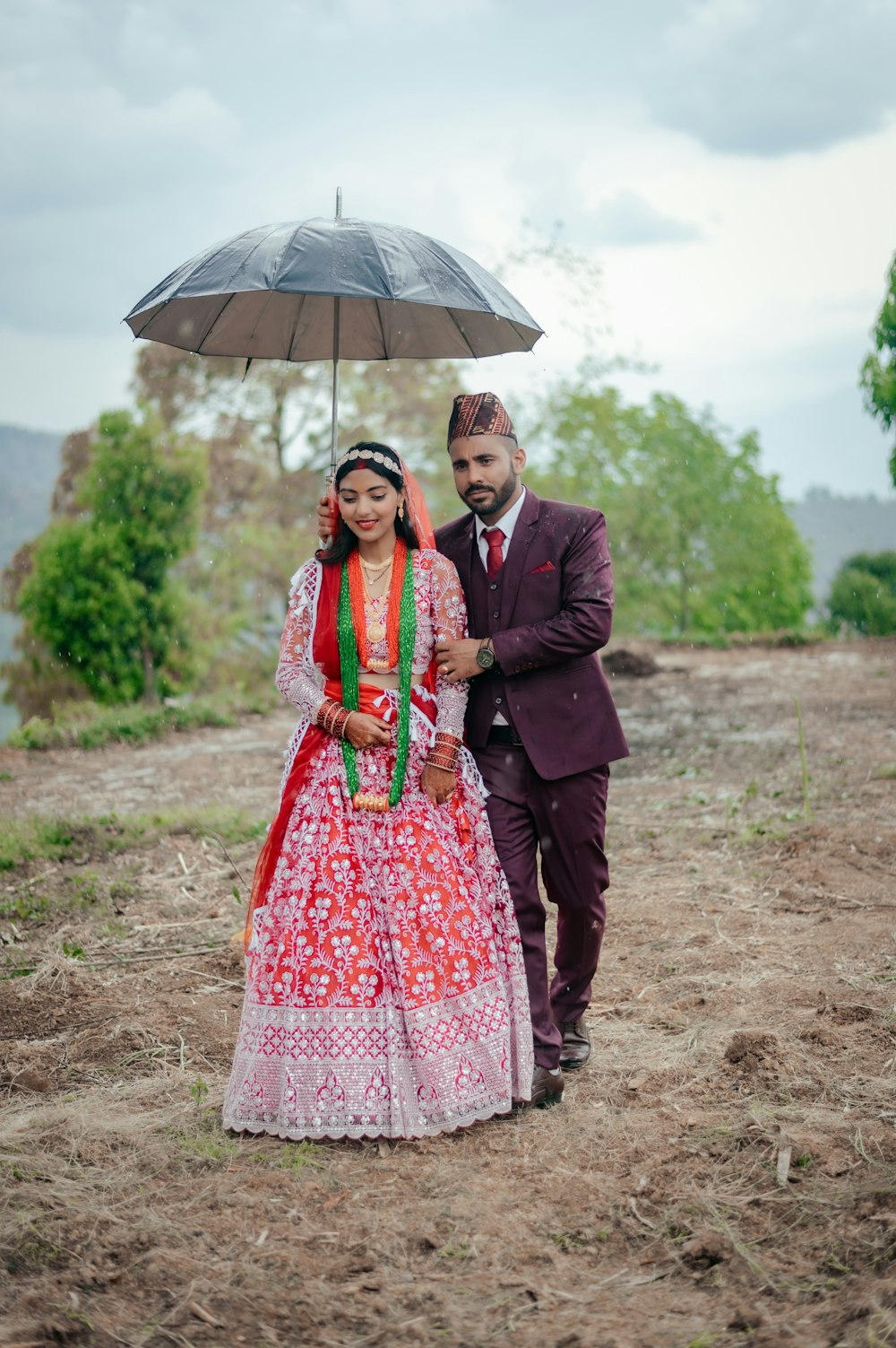 a man and a woman dressed in indian attire standing under an umbrella