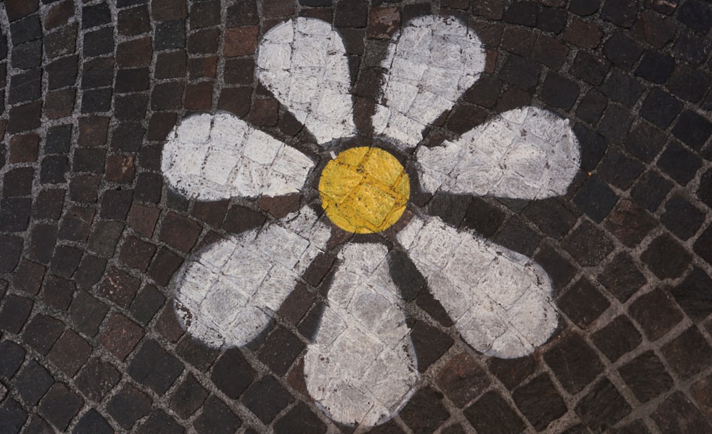 a white and yellow flower painted on a brick sidewalk