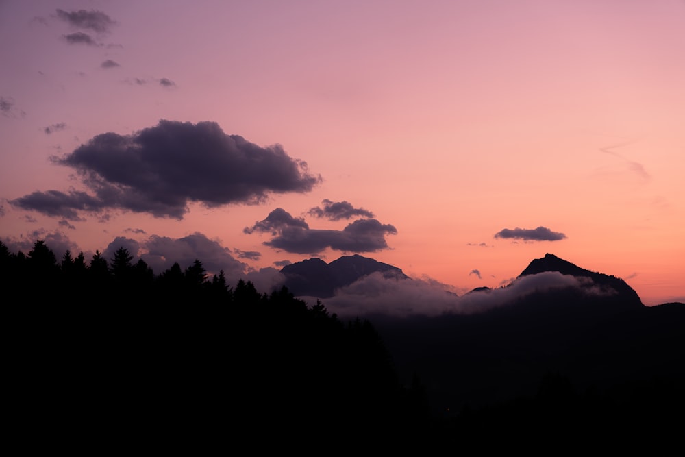 a sunset with clouds and mountains in the background