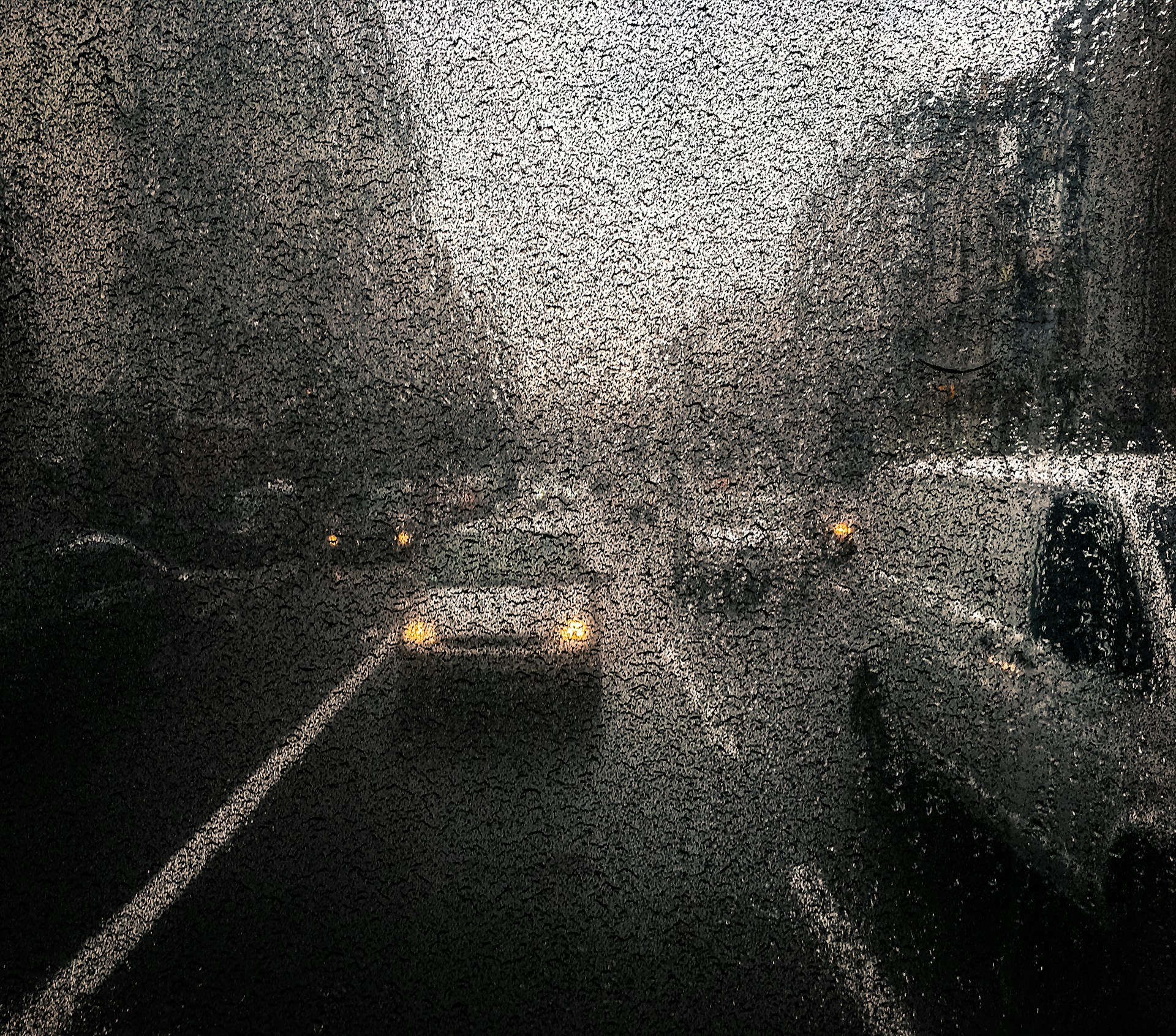 A street scene shot through a rain-speckled window, where blurred neon lights and reflections merge, turning an everyday moment into a mysterious, dreamlike composition.