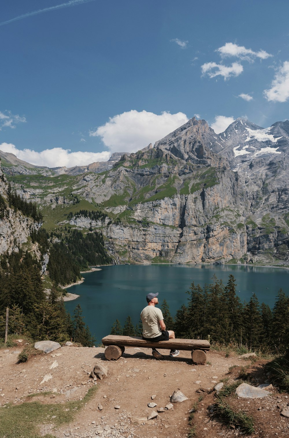 a man sitting on a bench overlooking a mountain lake