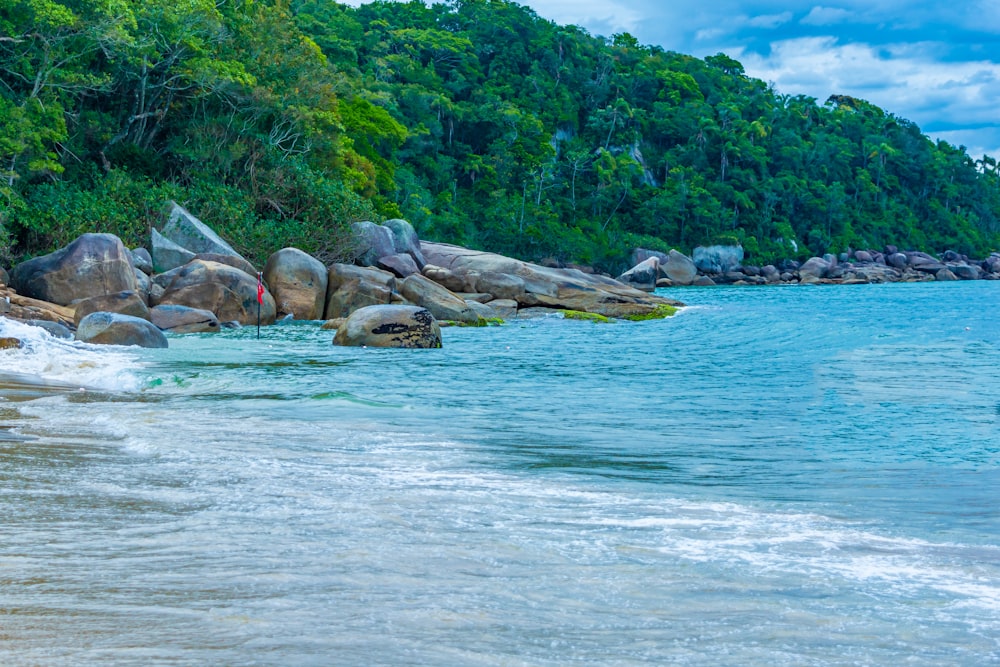 a sandy beach with large rocks and water