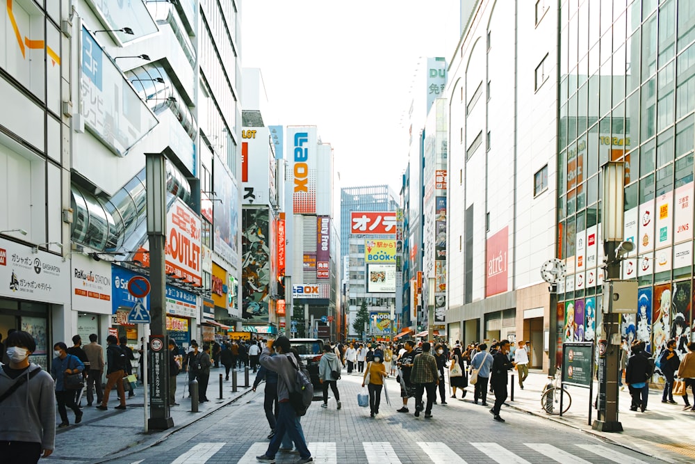 a group of people walking down a street next to tall buildings