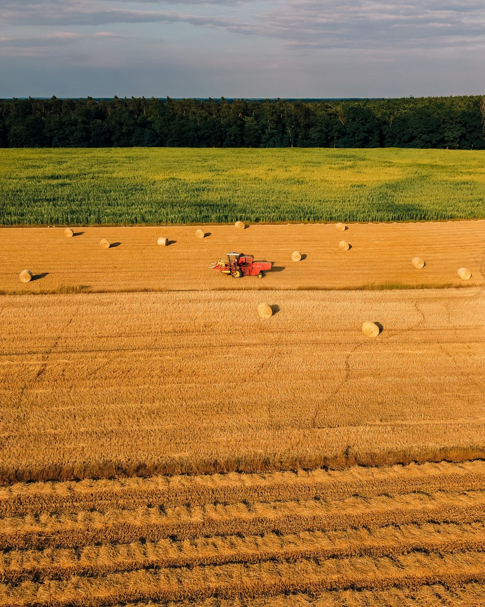 a farm field with a tractor and bales of hay