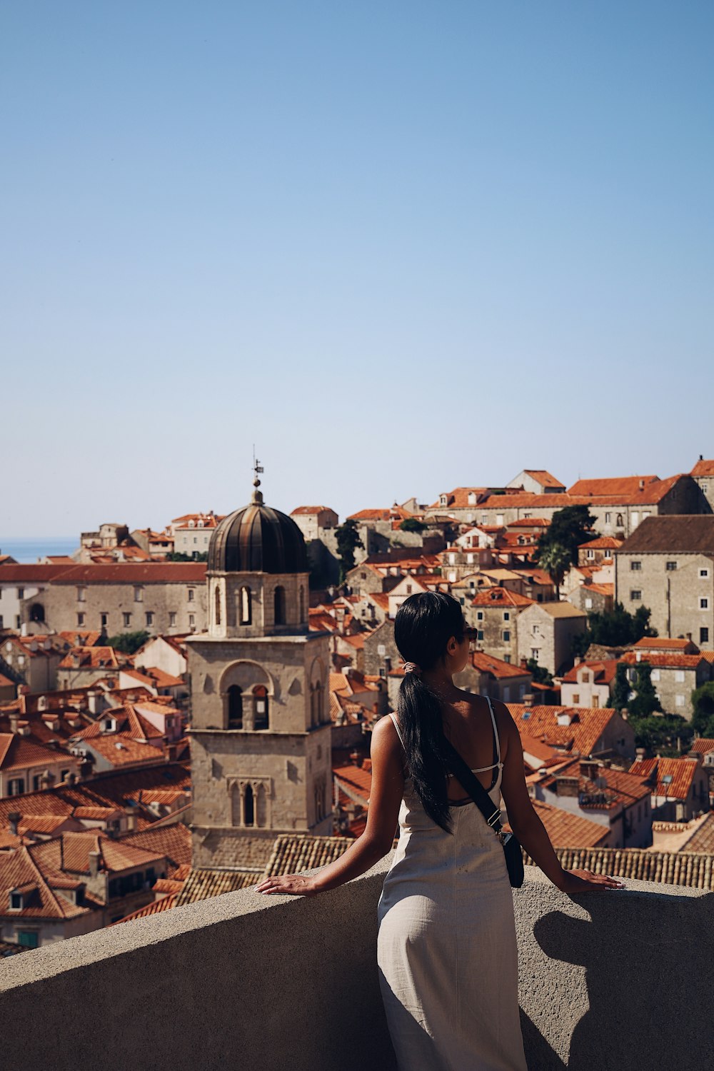 a woman standing on top of a building next to a city