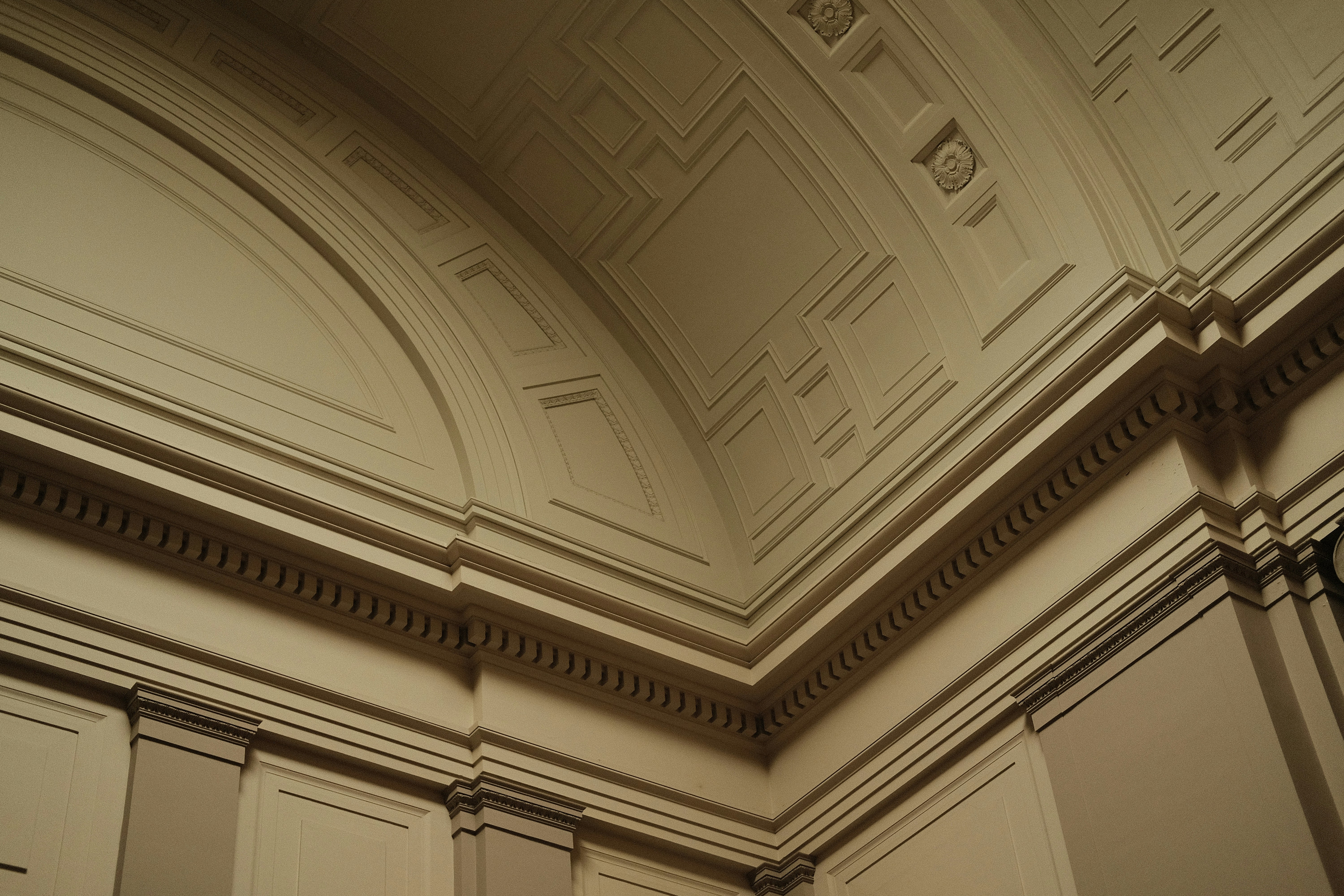 Ornate architectural details featuring intricate moldings and geometric patterns on a curved interior ceiling and wall.