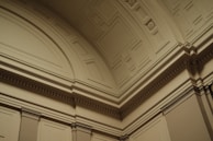 Ornate architectural details featuring intricate moldings and geometric patterns on a curved interior ceiling and wall.