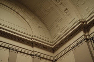 Ornate architectural details featuring intricate moldings and geometric patterns on a curved interior ceiling and wall.