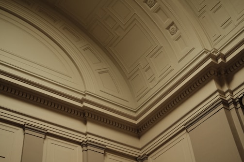 Ornate architectural details featuring intricate moldings and geometric patterns on a curved interior ceiling and wall.