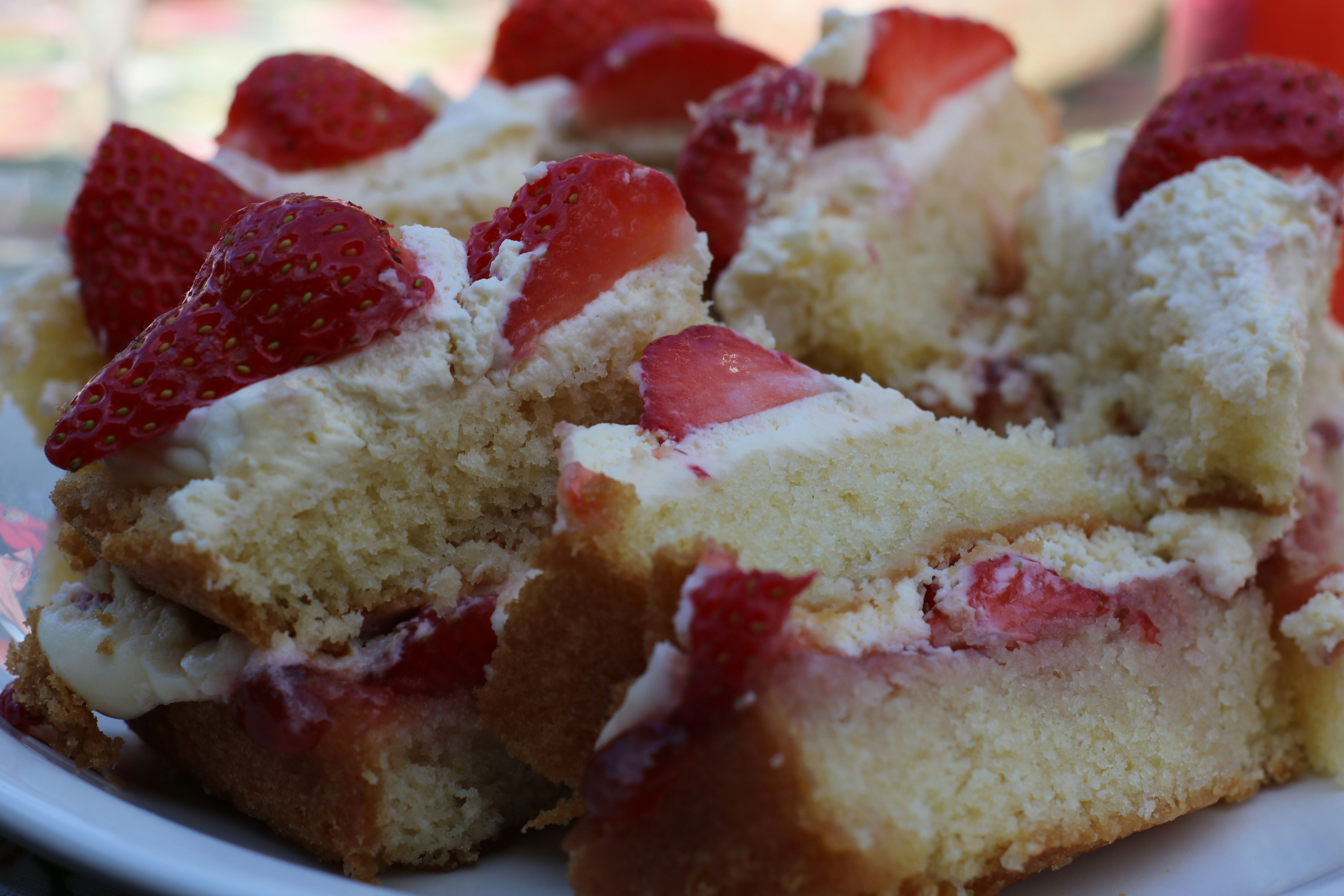 Tall strawberry cake with fresh strawberries on top, pink frosting, white cream layers, bright natural light