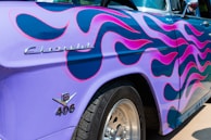 A classic muscle car adorned with a bright flame paint design, captured from the side.