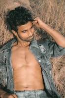 a shirtless man laying in a field of dry grass