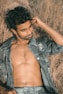 a shirtless man laying in a field of dry grass