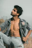 a shirtless man sitting in a field of tall grass